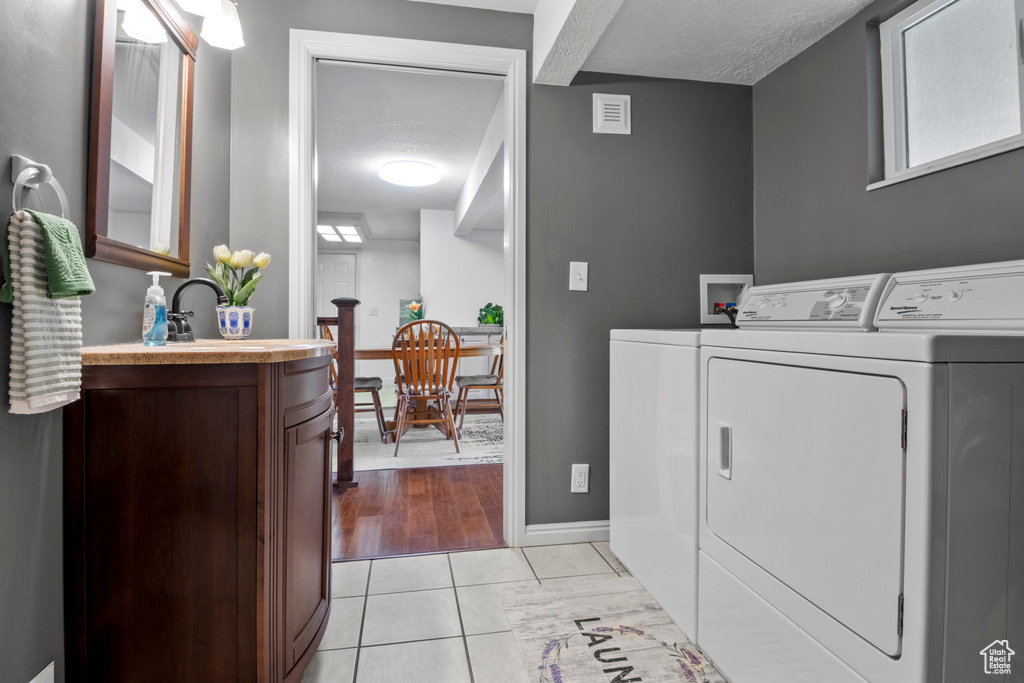 Laundry room featuring washer and dryer, baseboards, and a textured ceiling