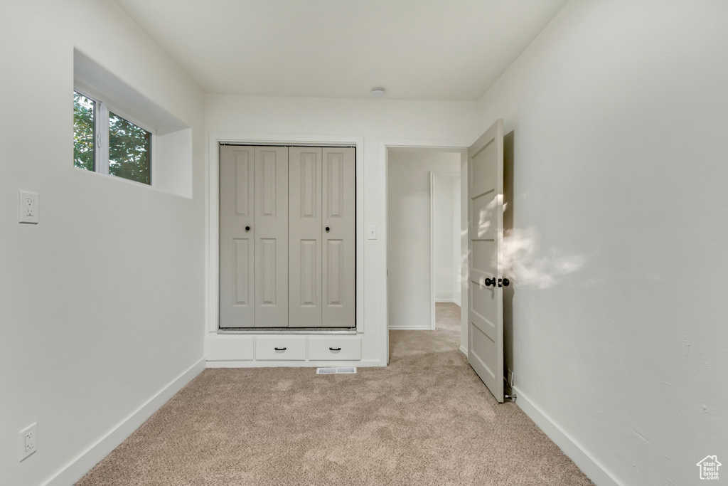 Unfurnished bedroom featuring light carpet and baseboards