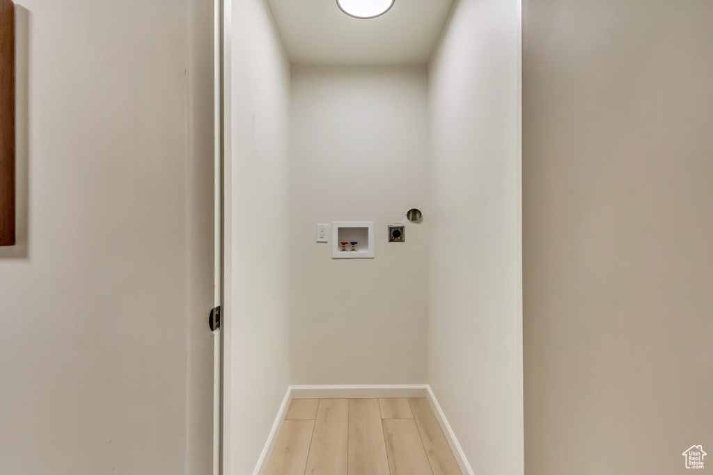 Clothes washing area with light wood-style flooring, electric dryer hookup, washer hookup, and baseboards