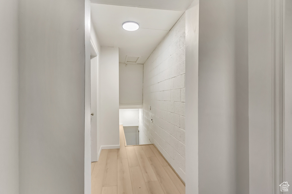 Corridor featuring light wood-style floors and concrete block wall