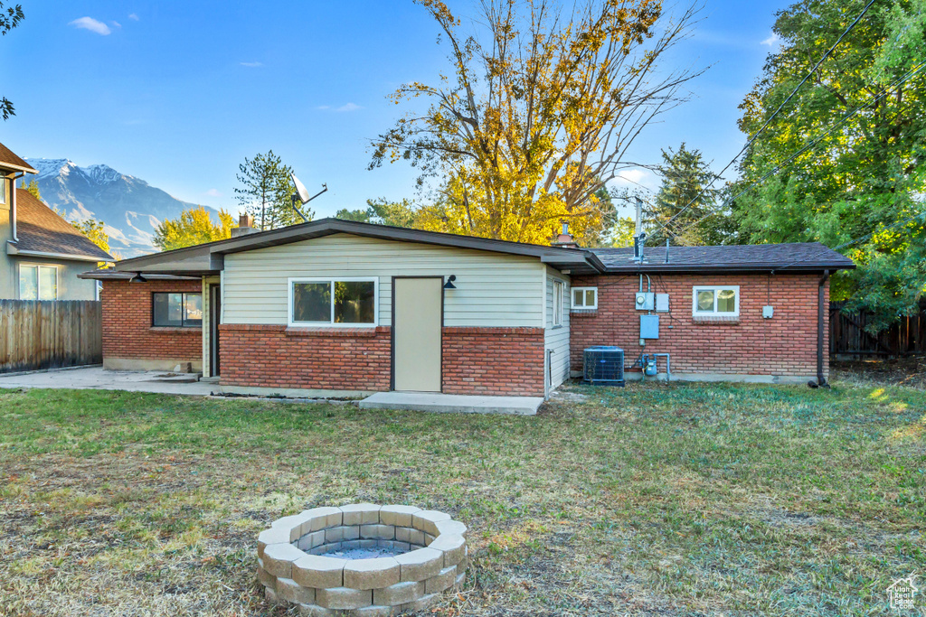Rear view of property featuring brick siding, central air condition unit, a mountain view, a fire pit, and a patio area