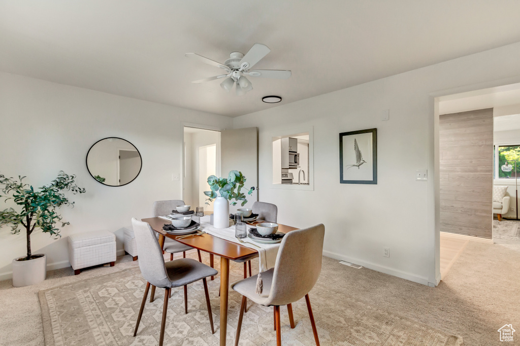 Dining area featuring light colored carpet, ceiling fan, and baseboards
