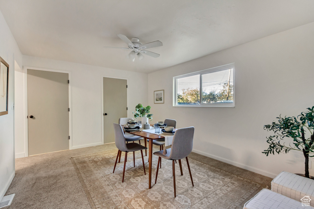 Dining room with a ceiling fan, light carpet, and baseboards