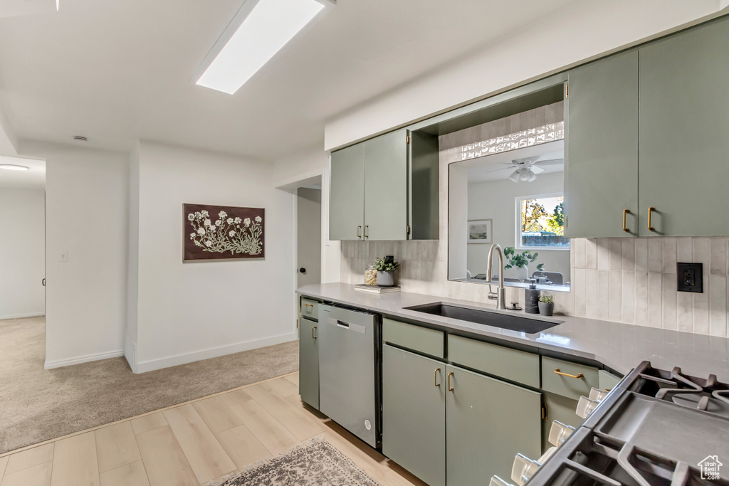 Kitchen with a sink, stainless steel dishwasher, light wood-style floors, tasteful backsplash, and green cabinetry