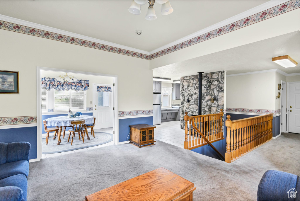 Carpeted living area featuring ornamental molding and a chandelier