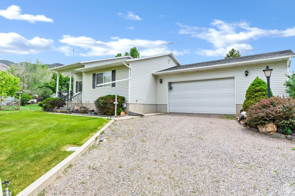 Ranch-style home with driveway, an attached garage, a front lawn, and a mountain view