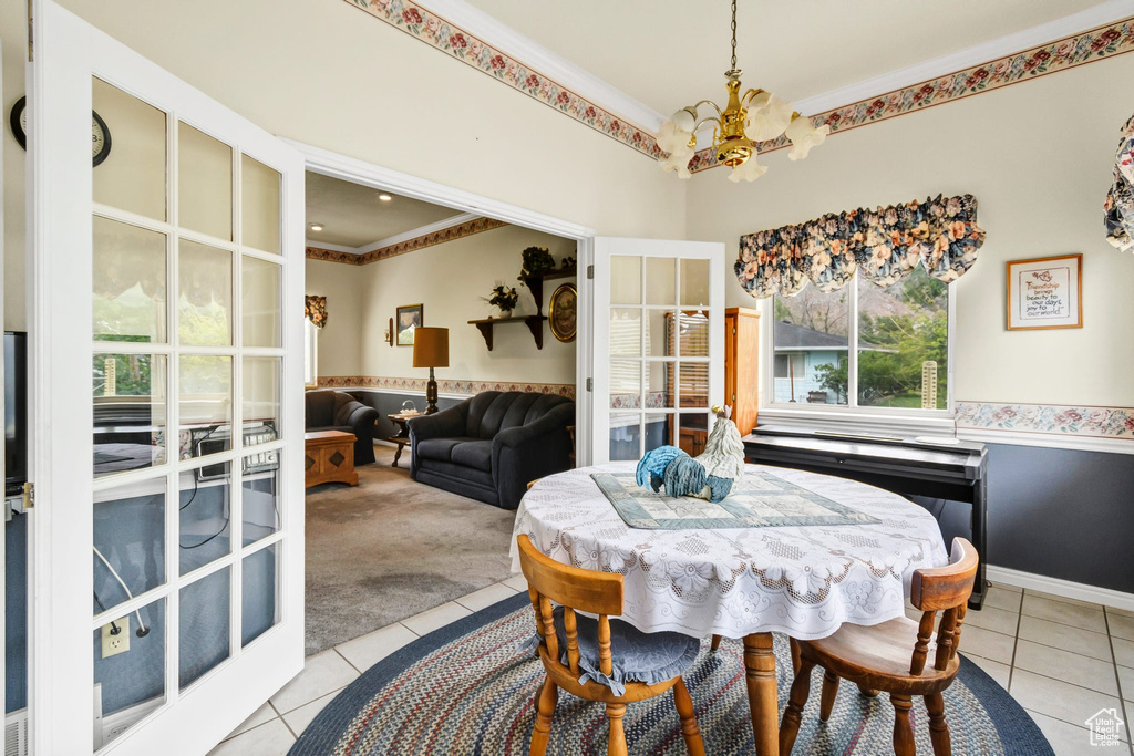 Dining room featuring a chandelier, light tile patterned flooring, light carpet, and crown molding