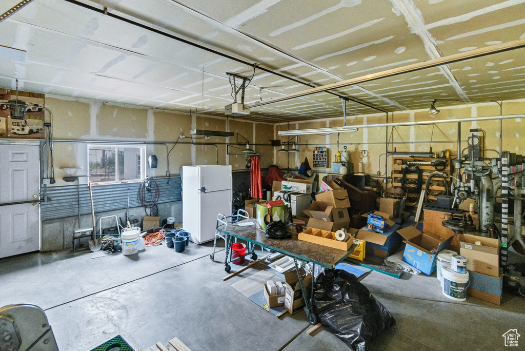 Garage featuring freestanding refrigerator and a garage door opener