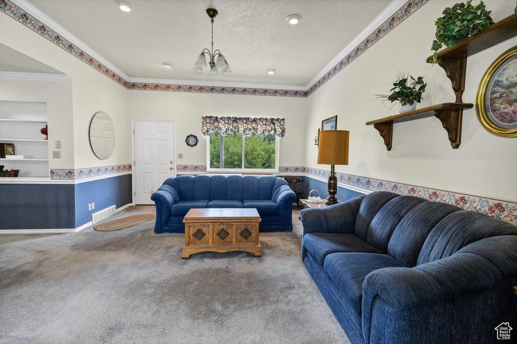 Carpeted living room with a chandelier, crown molding, and built in shelves