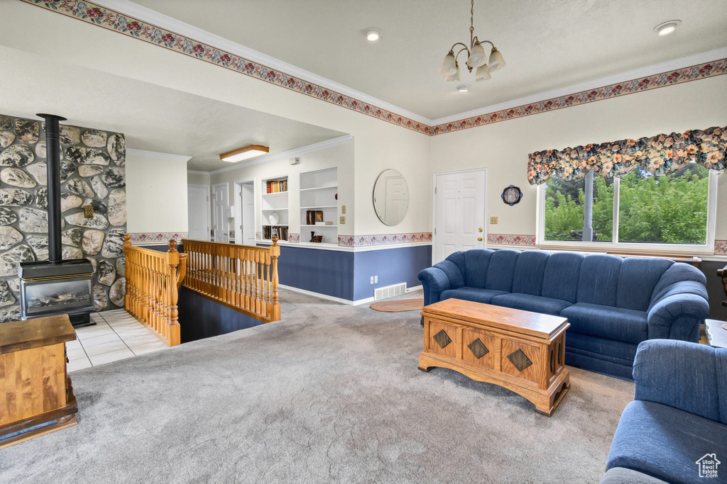 Living room featuring a chandelier, crown molding, a wood stove, and carpet flooring