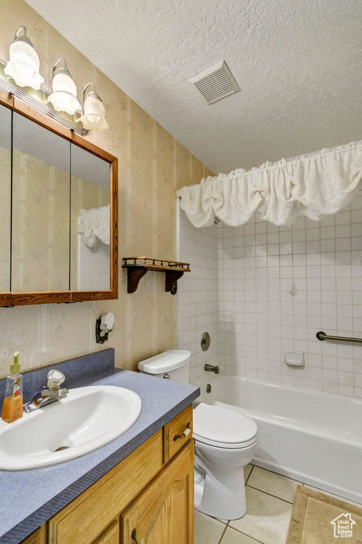 Full bathroom featuring tile patterned floors, toilet, vanity, a textured ceiling, and shower / tub combination