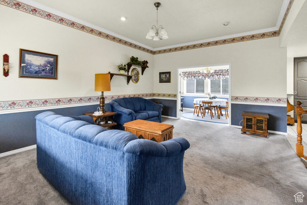Carpeted living room with a chandelier, ornamental molding, and baseboards