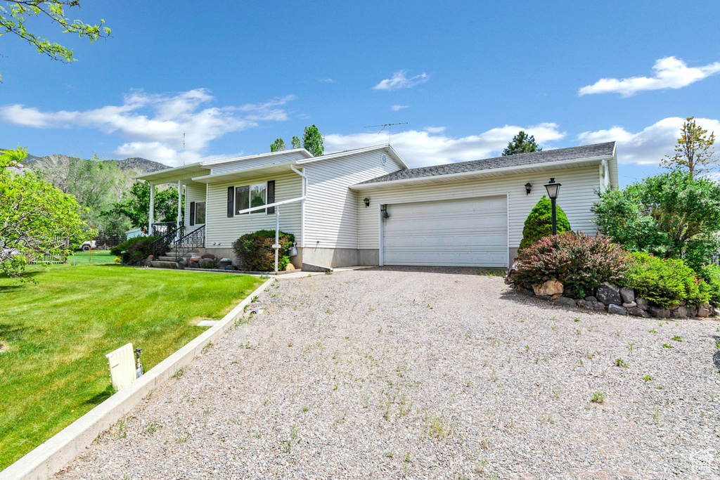 Single story home featuring driveway, an attached garage, and a front lawn