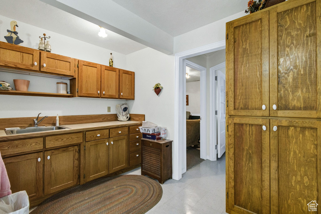 Kitchen with a sink, brown cabinets, open shelves, light countertops, and light tile patterned flooring