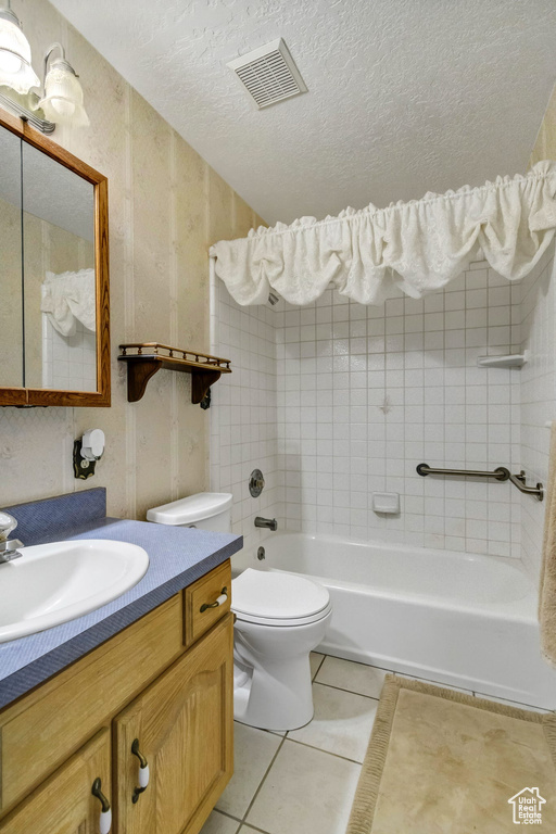 Full bathroom featuring tile patterned flooring, toilet, vanity, a textured ceiling, and bathing tub / shower combination