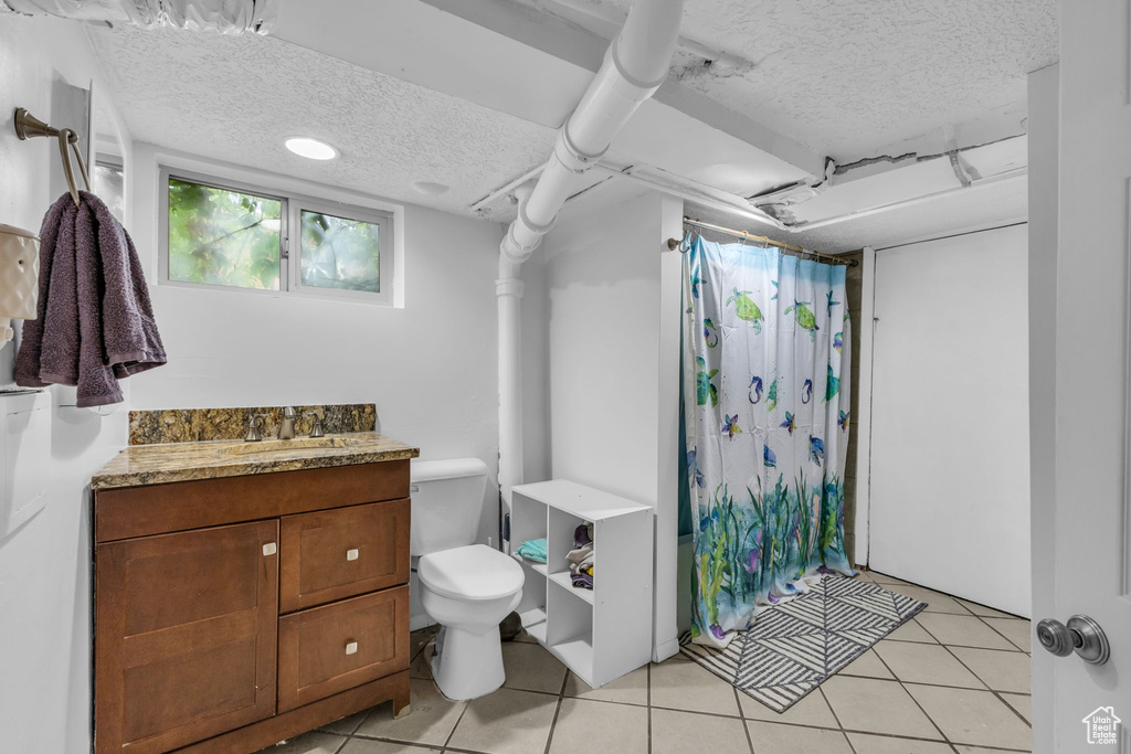 Bathroom with a textured ceiling, tile patterned flooring, toilet, a shower with curtain, and vanity