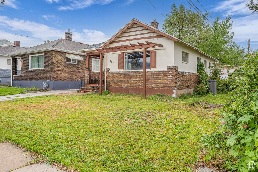 Bungalow-style home with a chimney, brick siding, and a front lawn