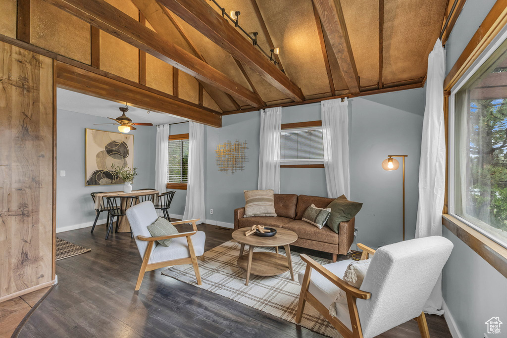 Living room with plenty of natural light, a ceiling fan, dark wood-type flooring, and baseboards