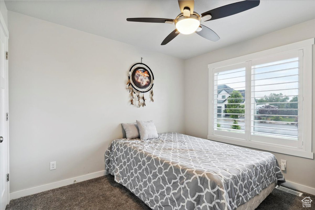 Bedroom with dark carpet, baseboards, and a ceiling fan