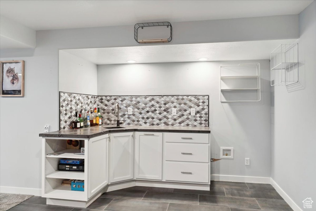 Kitchen with a sink, open shelves, dark countertops, decorative backsplash, and white cabinetry