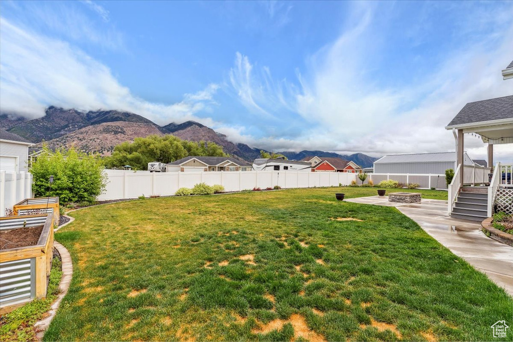 View of yard with an outdoor fire pit, a patio, a mountain view, and a garden