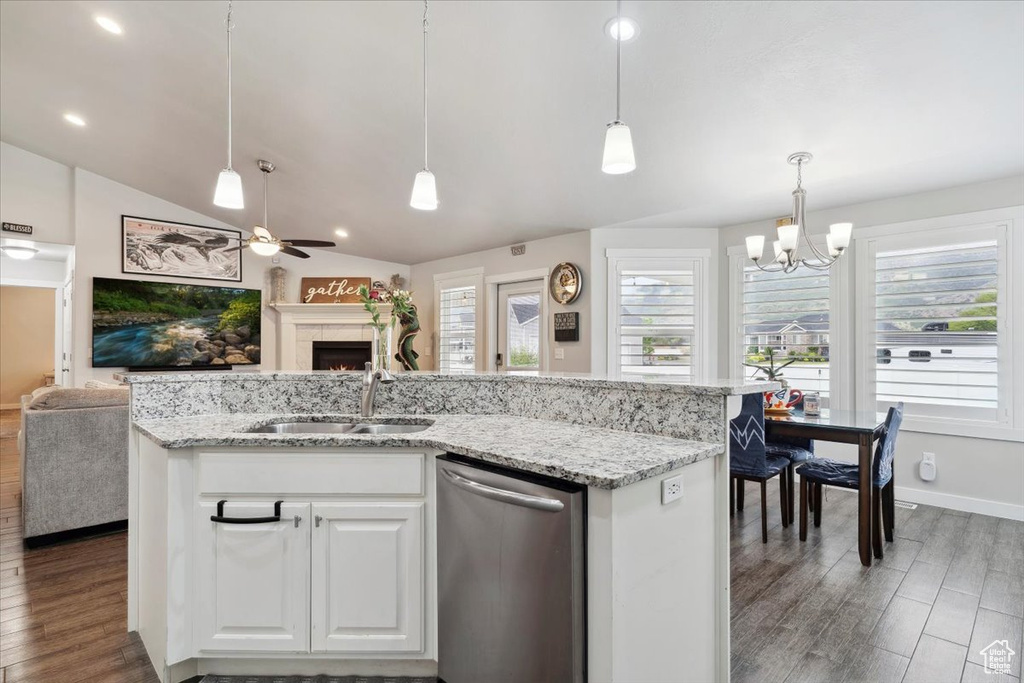 Kitchen featuring dishwasher, open floor plan, a sink, a lit fireplace, and vaulted ceiling
