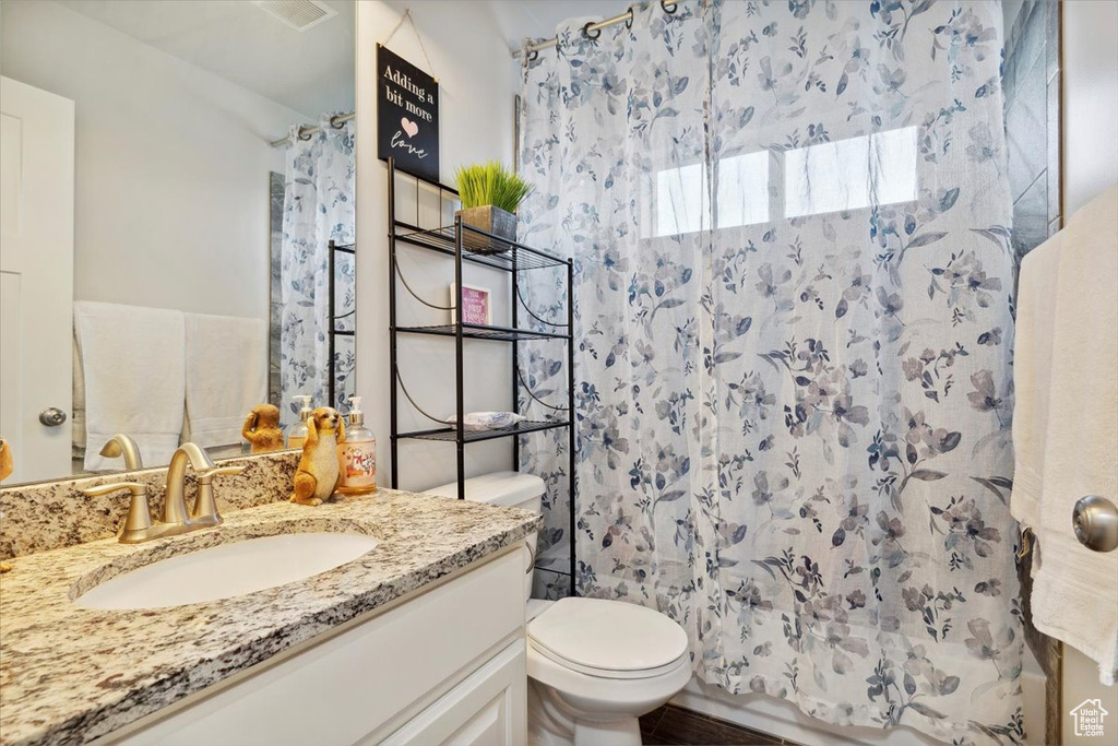 Bathroom featuring toilet, curtained shower, and vanity