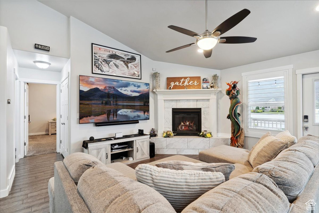 Living room with lofted ceiling, light wood-style flooring, ceiling fan, a fireplace, and baseboards