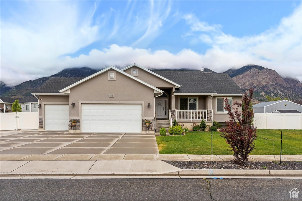 View of front of home featuring stucco siding, a mountain view, stone siding, and a garage