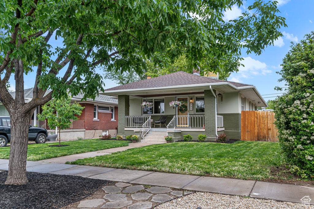 Bungalow-style home with a porch, brick siding, and roof with shingles