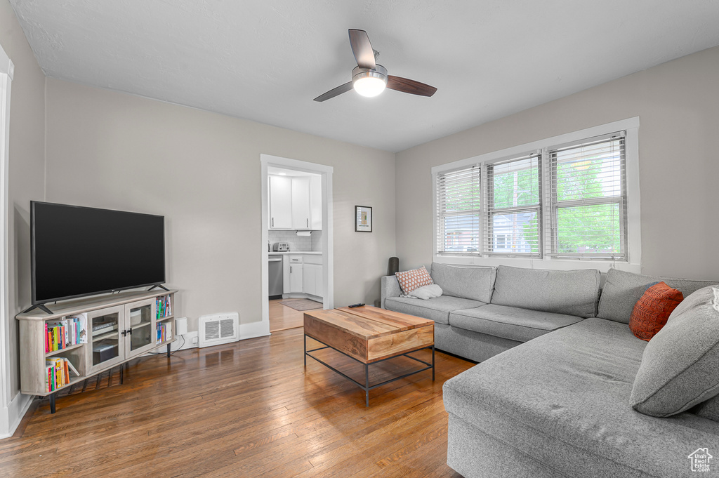 Living room with hardwood / wood-style floors, ceiling fan, and baseboards