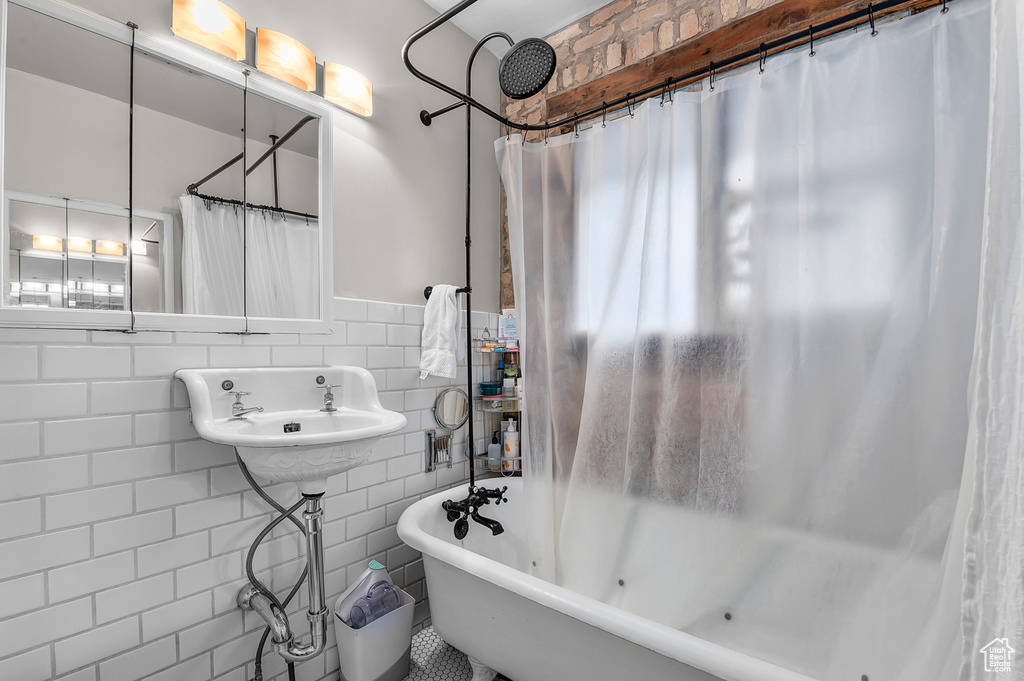 Bathroom featuring tile walls, a bathtub, wainscoting, a shower with curtain, and a sink
