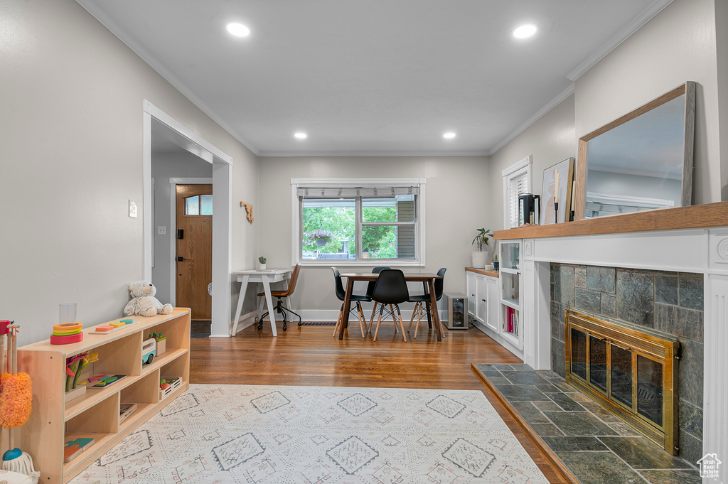 Living area featuring crown molding, recessed lighting, wood finished floors, a tiled fireplace, and baseboards