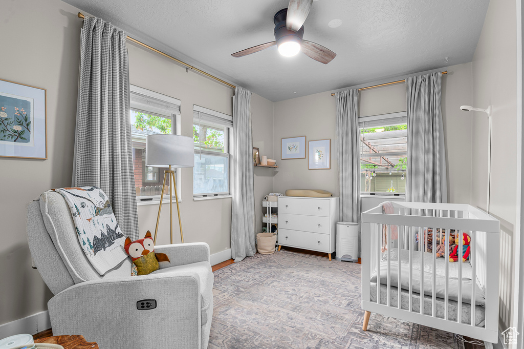 Bedroom with a nursery area, a ceiling fan, and baseboards