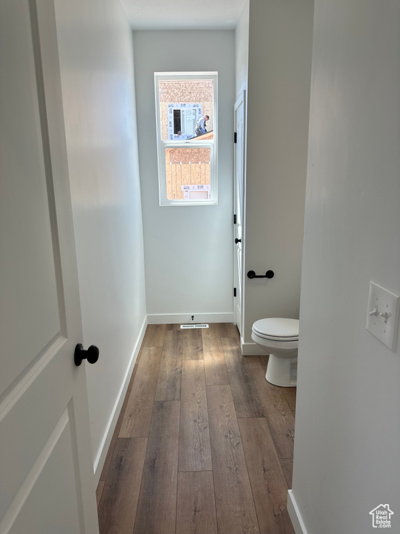 Bathroom featuring hardwood / wood-style flooring, baseboards, and toilet