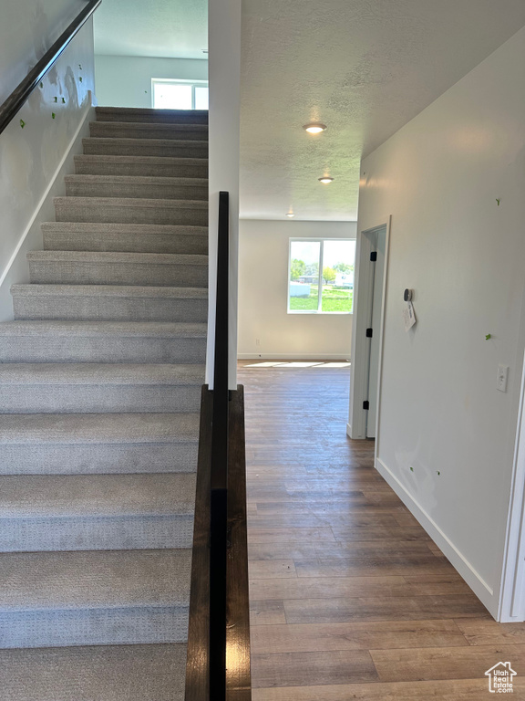 Stairway featuring wood finished floors, baseboards, and a textured ceiling