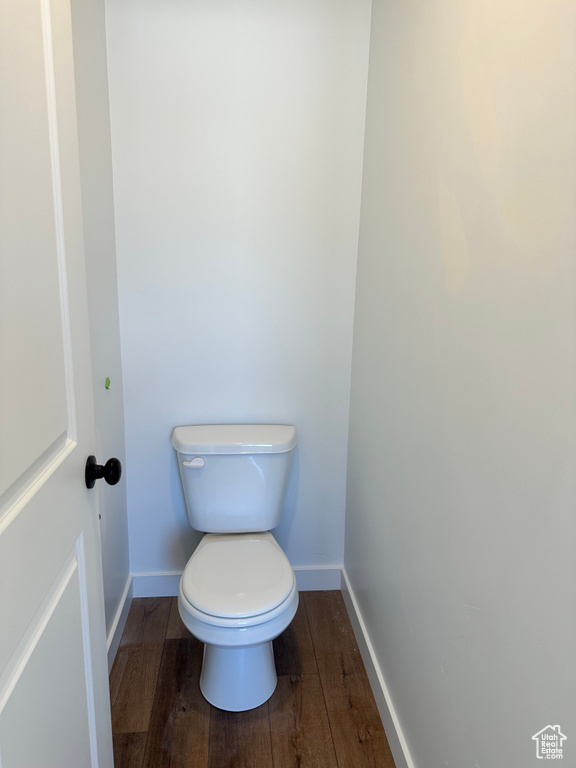 Bathroom with wood finished floors, baseboards, and toilet