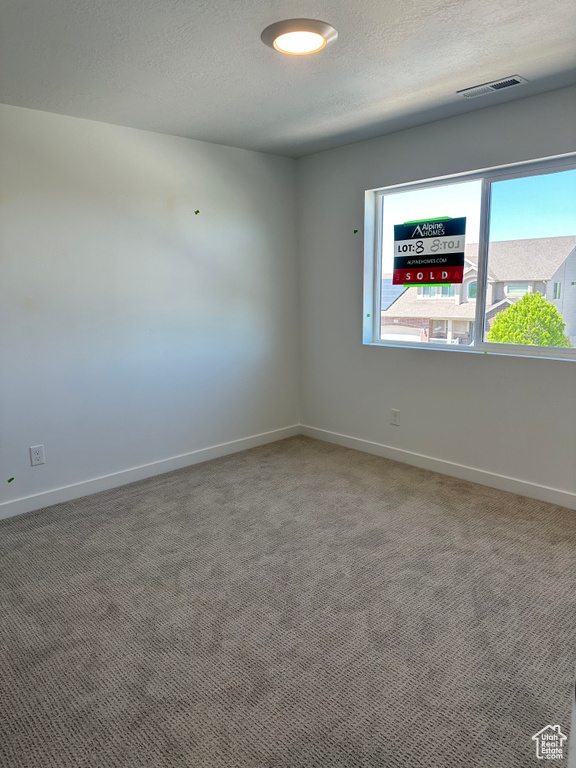 Spare room featuring baseboards, carpet flooring, and a textured ceiling