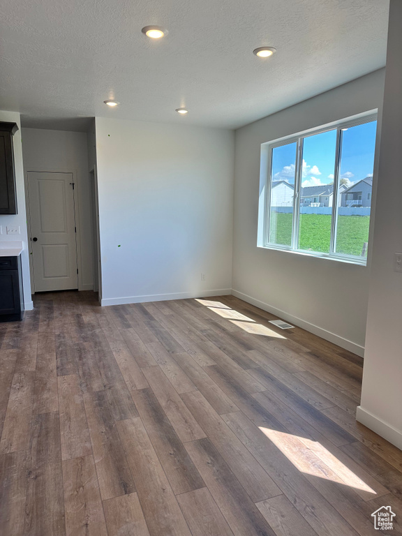Empty room with dark wood-style flooring, baseboards, and recessed lighting
