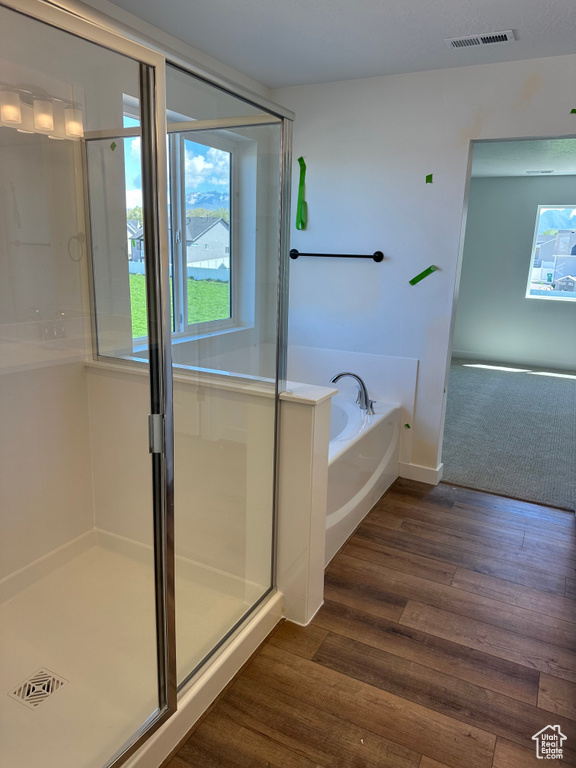 Full bath featuring a garden tub, a shower stall, and wood finished floors