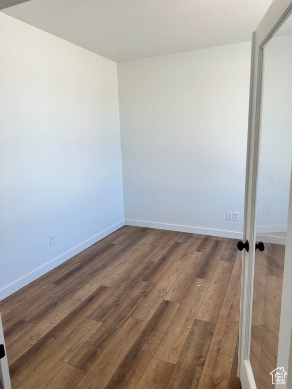 Unfurnished room featuring dark wood-type flooring and baseboards