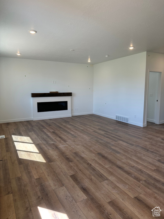 Unfurnished living room featuring a fireplace, dark wood-type flooring, recessed lighting, and baseboards