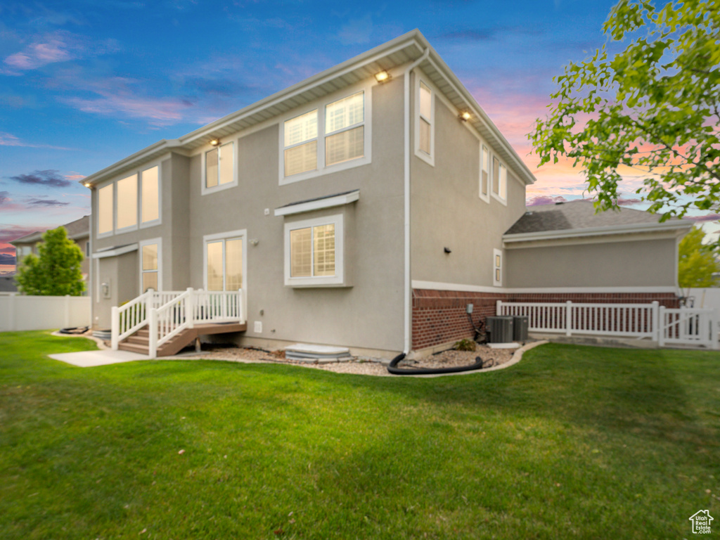 Rear view of property with brick siding, stucco siding, and central AC