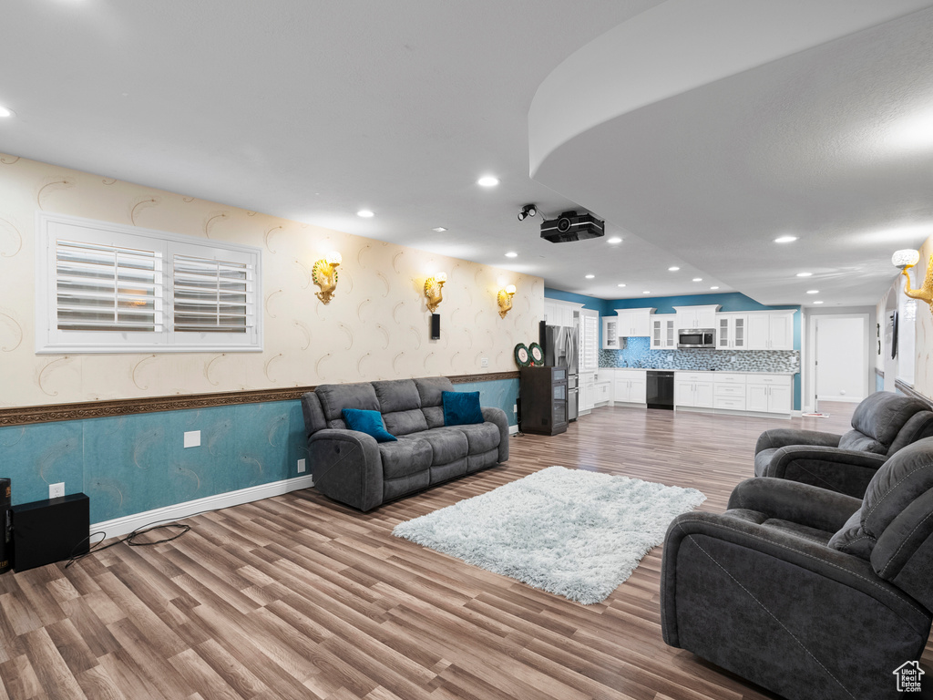 Living room featuring wood finished floors, recessed lighting, wallpapered walls, wainscoting, and baseboards