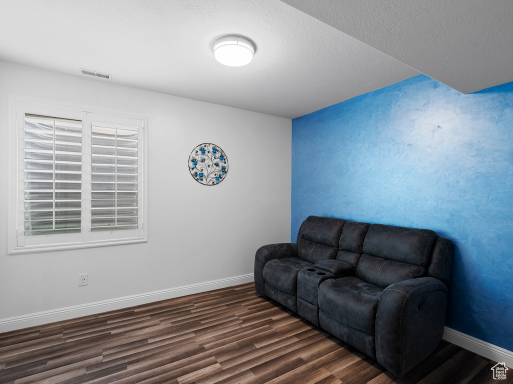 Living room with dark wood-style floors, baseboards, and a textured ceiling