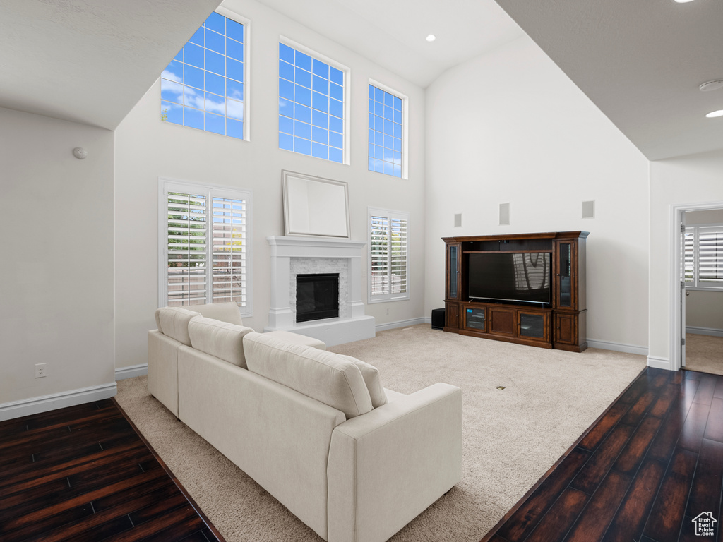 Living room with high vaulted ceiling, hardwood / wood-style floors, plenty of natural light, baseboards, and recessed lighting