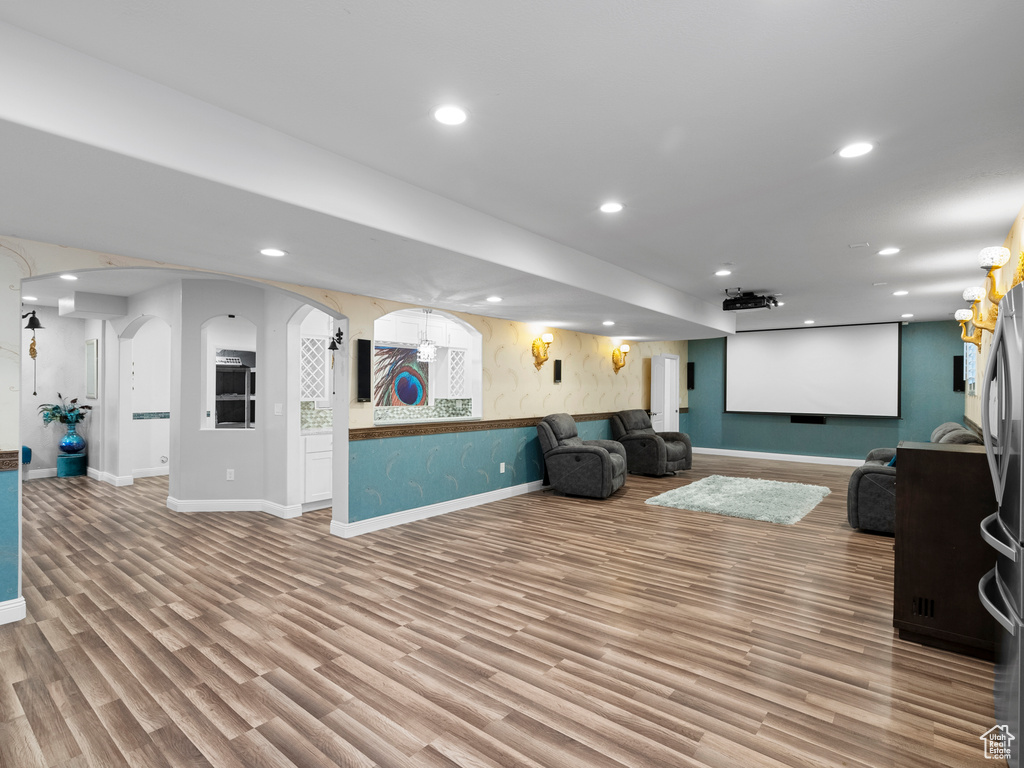 Cinema room with arched walkways, baseboards, recessed lighting, and wood finished floors