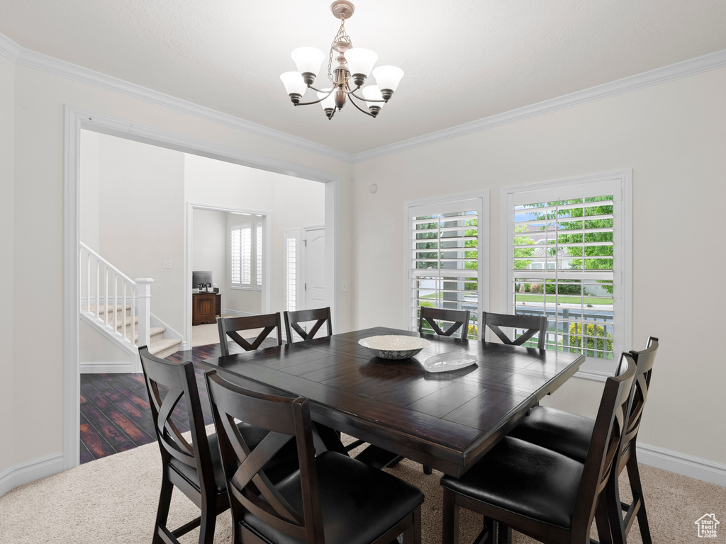 Dining room with a chandelier, ornamental molding, stairs, baseboards, and carpet flooring