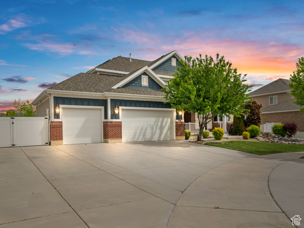 Craftsman-style house with a gate, a shingled roof, a garage, driveway, and brick siding