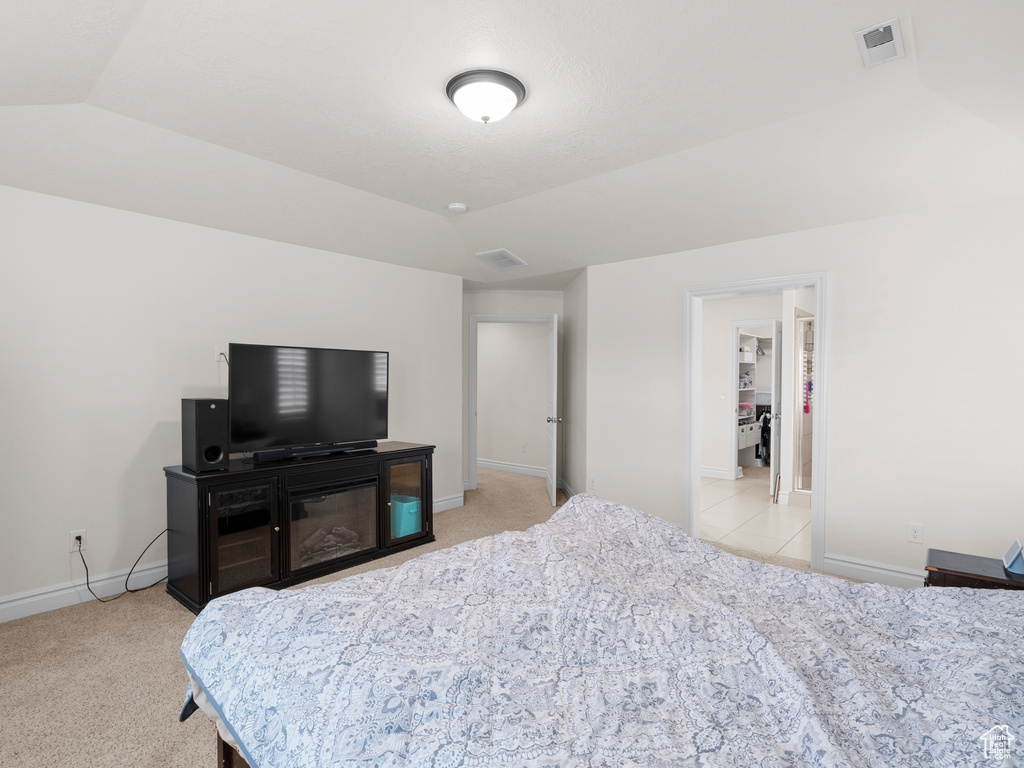 Bedroom with baseboards, light carpet, and vaulted ceiling